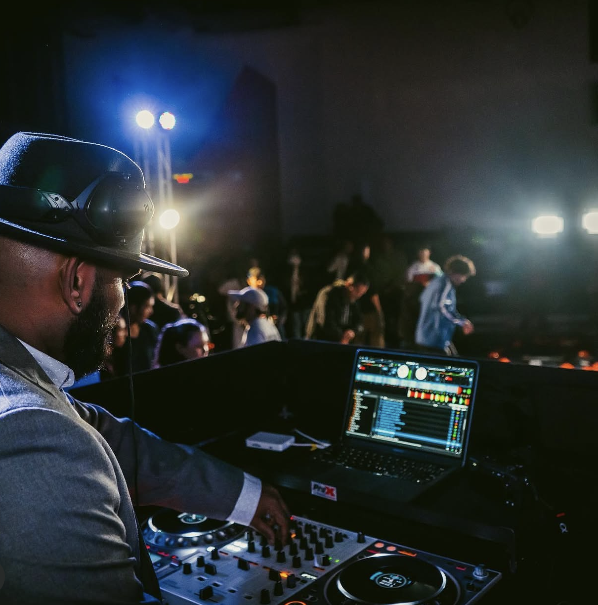 ILP DJ mixing live with guests dancing under moody blue and warm venue lighting