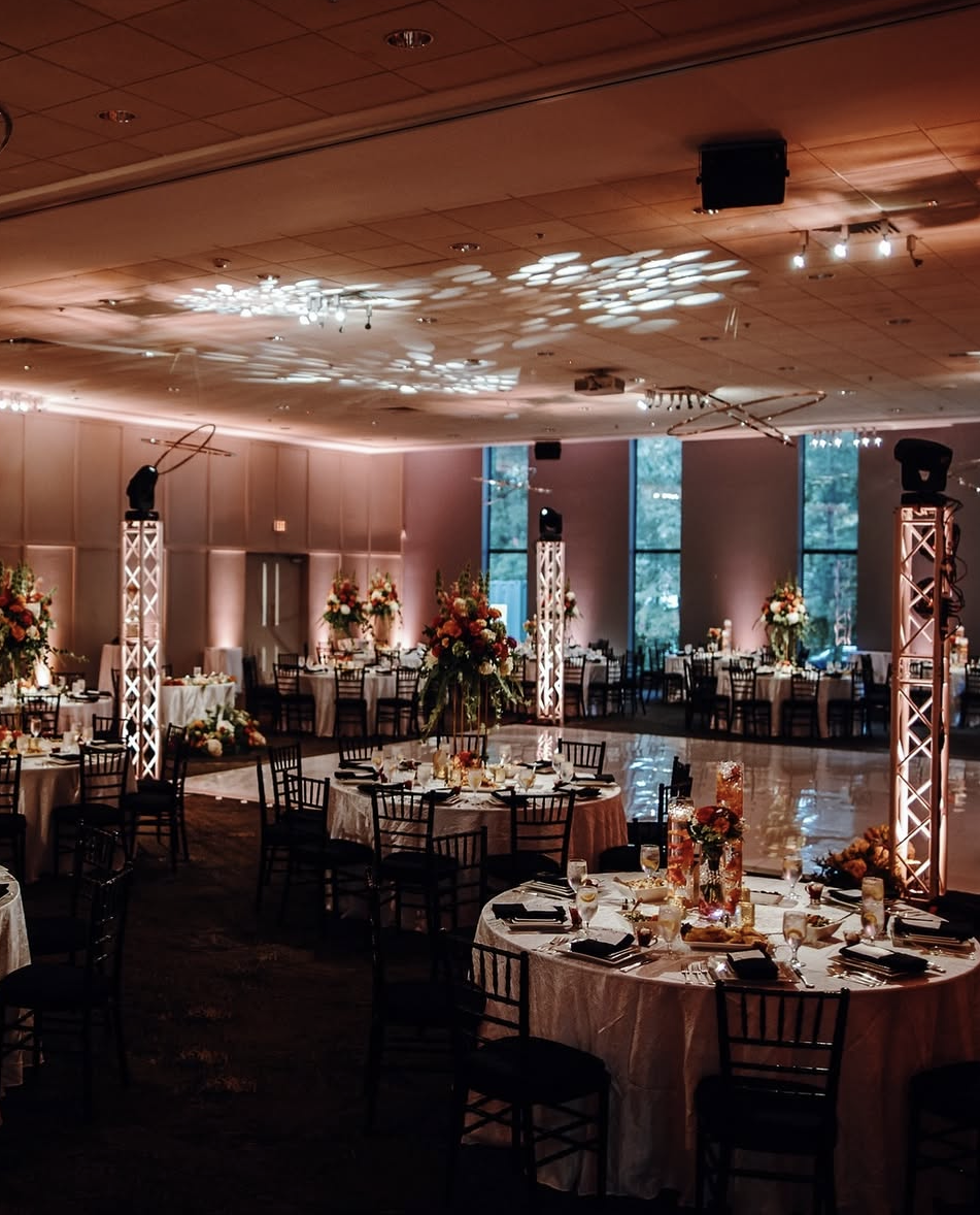 Elegant ballroom reception with warm uplighting, detailed table settings, and a polished dance floor