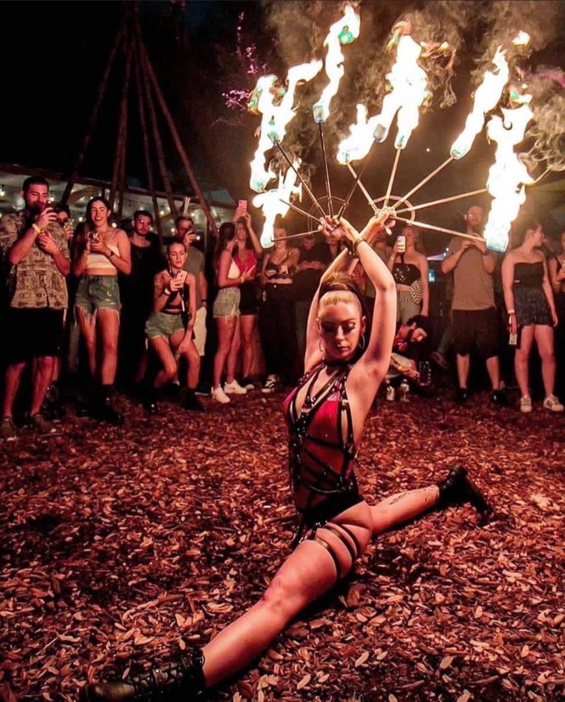Fire performer with flaming fans entertaining a crowd at an outdoor event